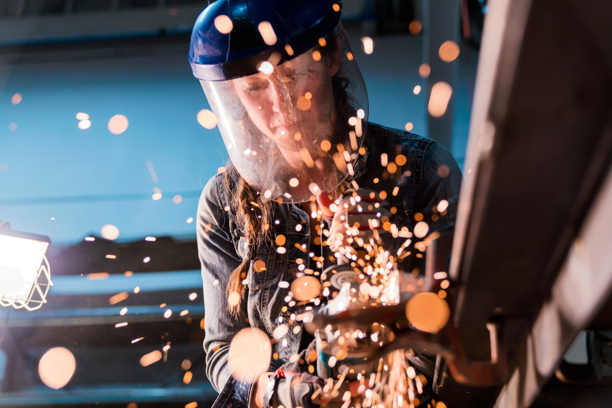 Eine Handwerkerin arbeitet mit einem Winkelschleifer in einer Werkstatt