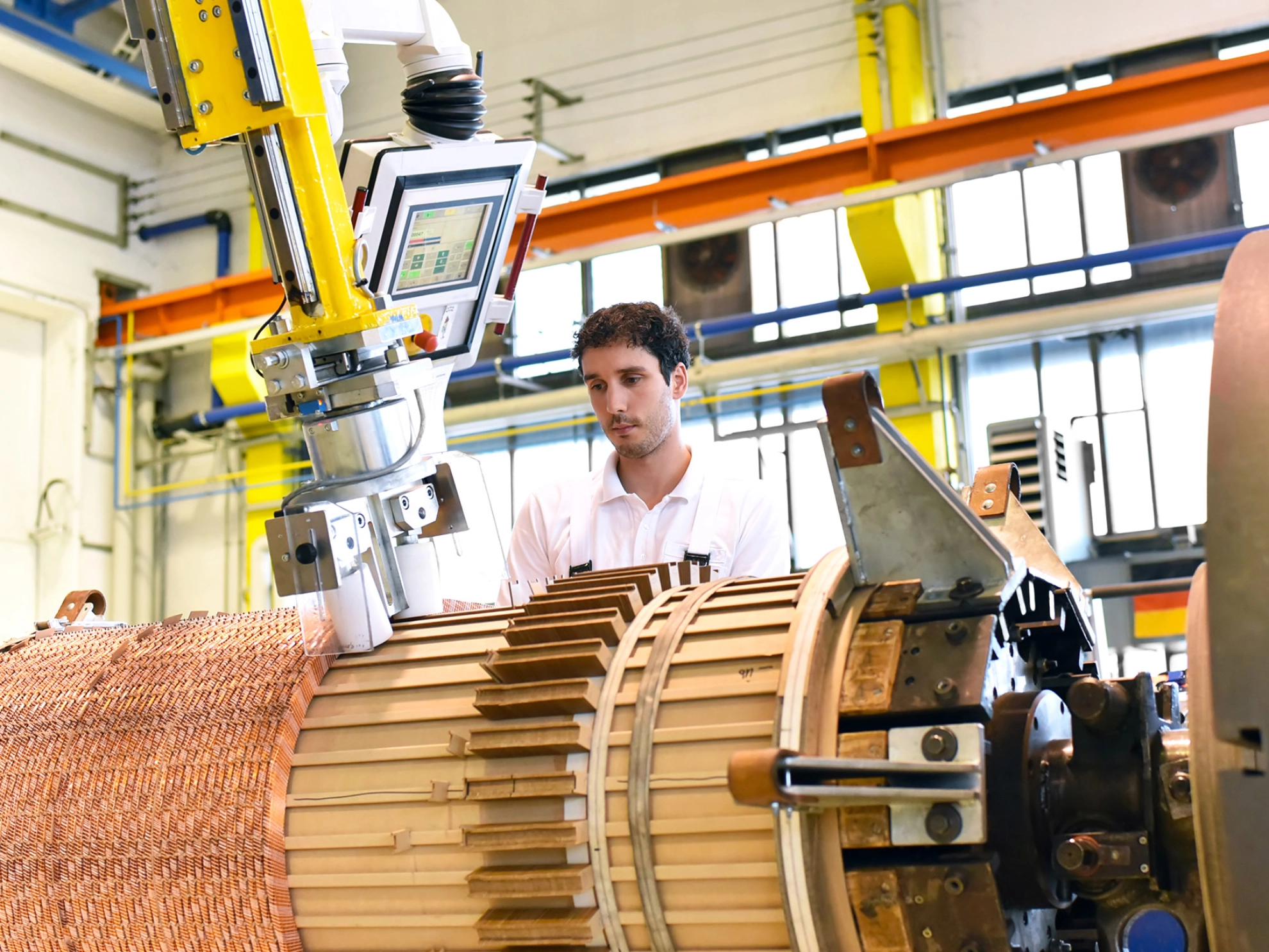 Ein junger Mann arbeitet an einer Maschine in einer Fabrik zur Herstellung von Transformatoren.
