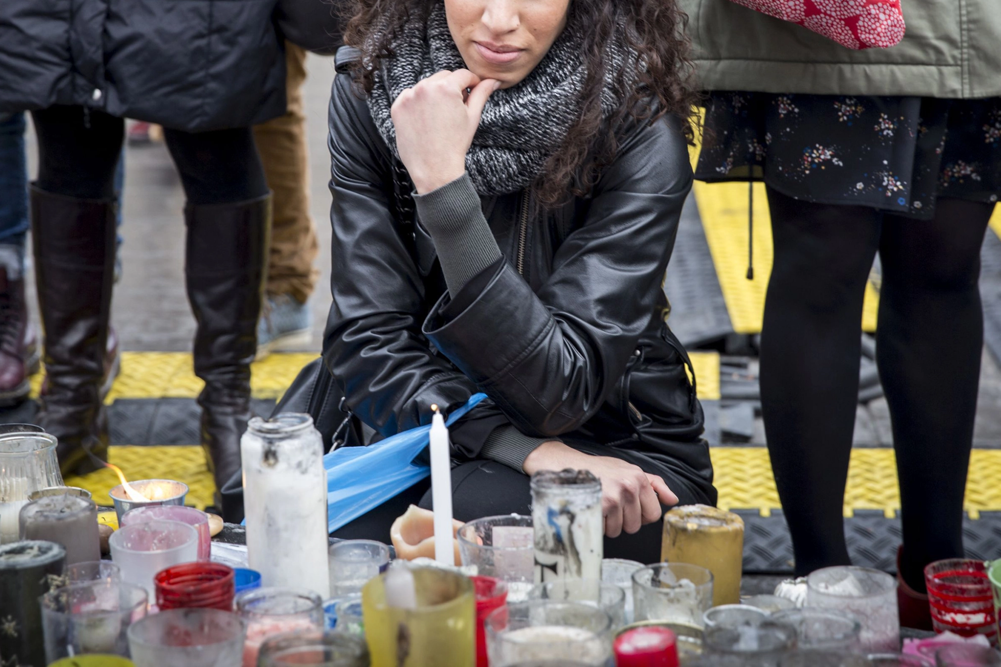 Teilnehmerin einer Trauerfeier kniet vor Kerzen und hält inne