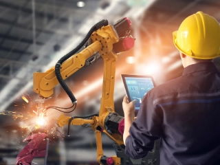 Ingenieur steuert mit Tablet einen Schweißroboter